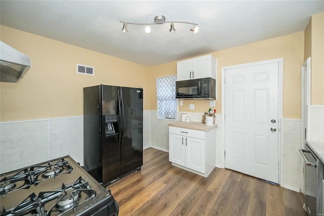 kitchen with white cabinets, dark hardwood / wood-style floors, black appliances, and tile walls