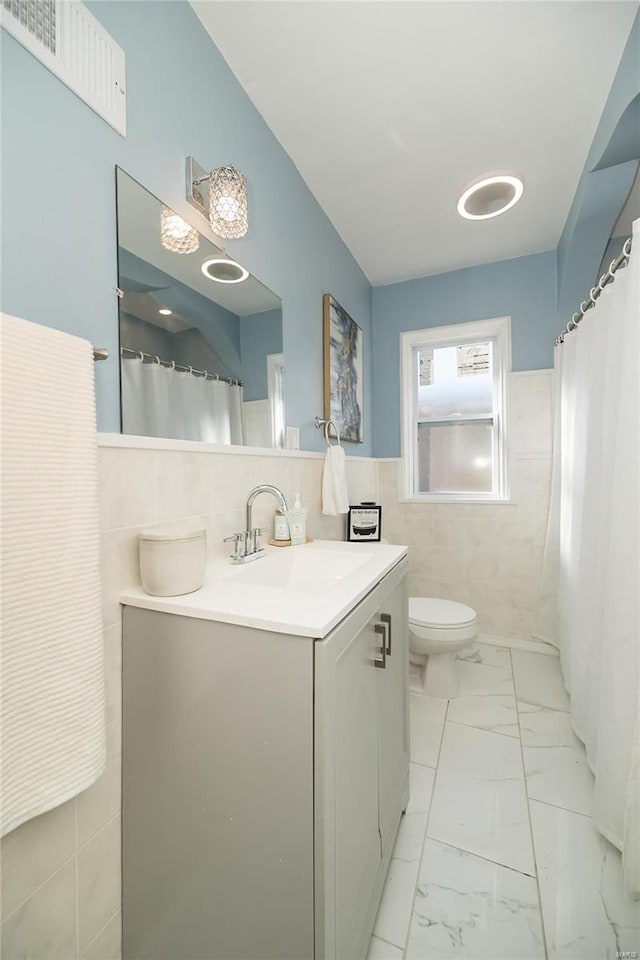 bathroom featuring vanity, toilet, and tile walls