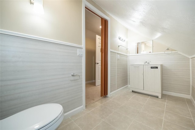 bathroom with toilet, tile patterned floors, vaulted ceiling, a textured ceiling, and vanity