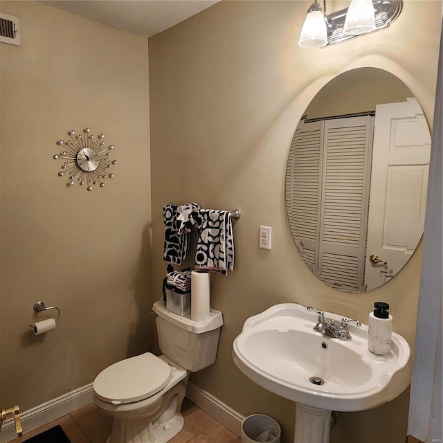 bathroom with toilet, sink, and tile patterned floors