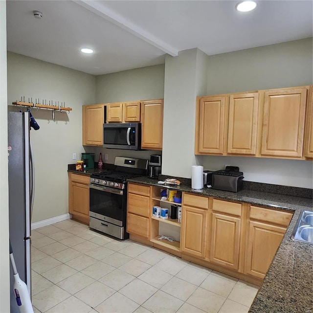 kitchen featuring dark stone counters, sink, light tile patterned floors, and stainless steel appliances