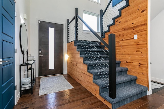 foyer featuring dark wood-type flooring and wooden walls