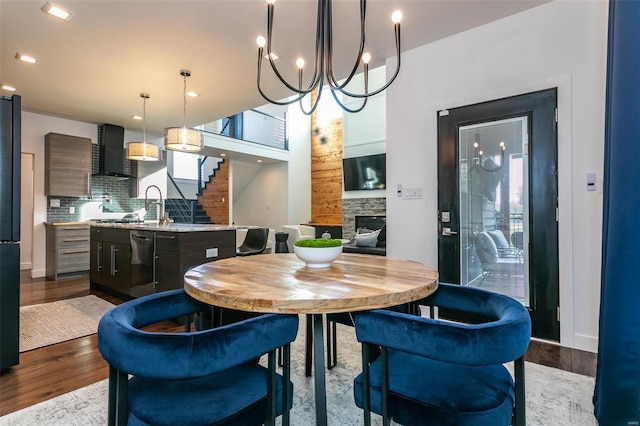 dining space with a fireplace, an inviting chandelier, sink, and light wood-type flooring