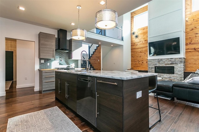 kitchen with a kitchen island with sink, dark hardwood / wood-style flooring, wood walls, and dishwasher