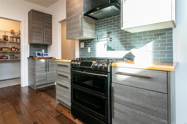 kitchen featuring dark hardwood / wood-style flooring, wall chimney exhaust hood, decorative backsplash, and range with two ovens