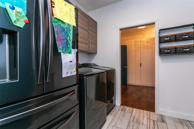 clothes washing area with light hardwood / wood-style flooring, washing machine and dryer, and cabinets