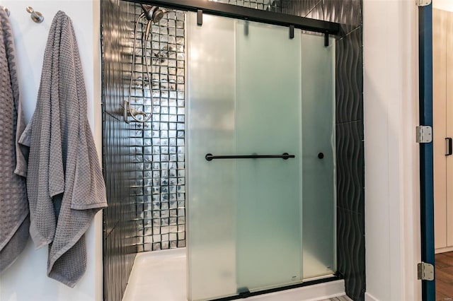 bathroom with wood-type flooring and a shower with shower door