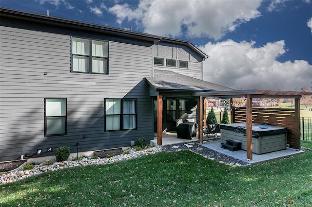 back of property with a lawn, a patio, and a hot tub