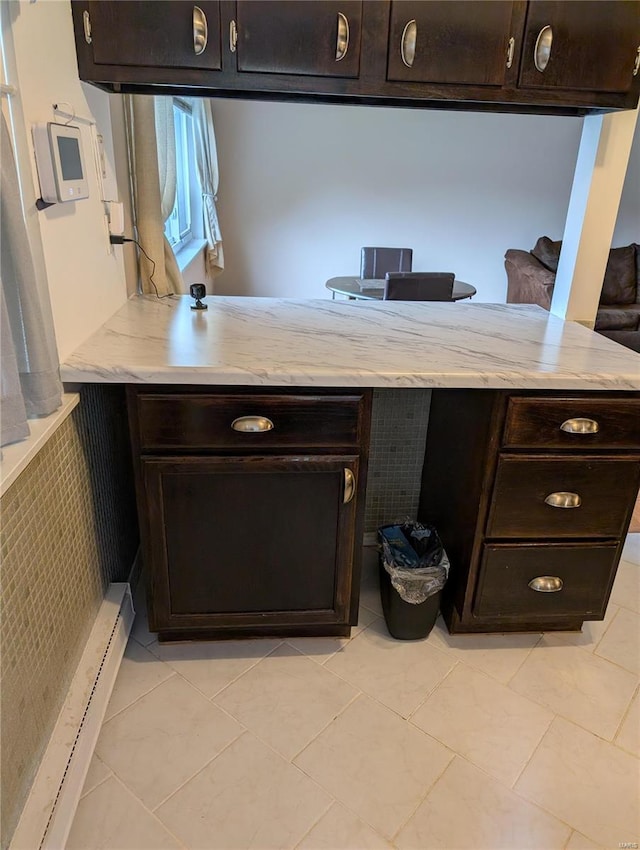 kitchen featuring kitchen peninsula, dark brown cabinets, light tile patterned flooring, and a baseboard heating unit