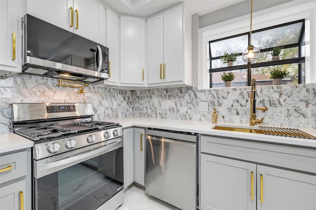 kitchen featuring appliances with stainless steel finishes, tasteful backsplash, white cabinetry, and decorative light fixtures