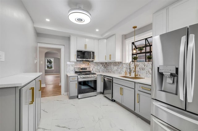 kitchen featuring appliances with stainless steel finishes, hanging light fixtures, a healthy amount of sunlight, and sink