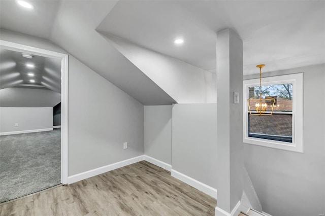 additional living space with wood-type flooring, vaulted ceiling, and a notable chandelier