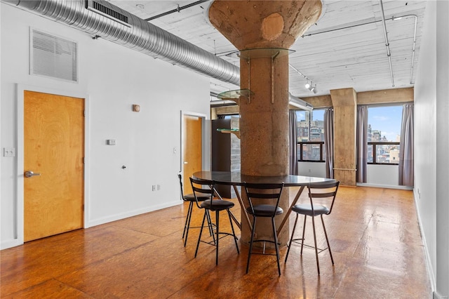 dining area featuring a high ceiling and concrete floors