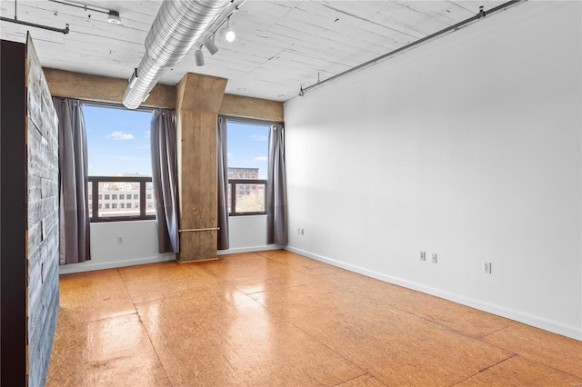 unfurnished room featuring rail lighting