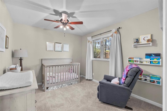 carpeted bedroom featuring ceiling fan and a nursery area