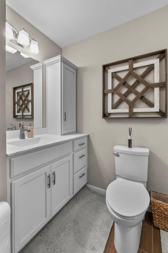 bathroom with toilet, wood-type flooring, and vanity