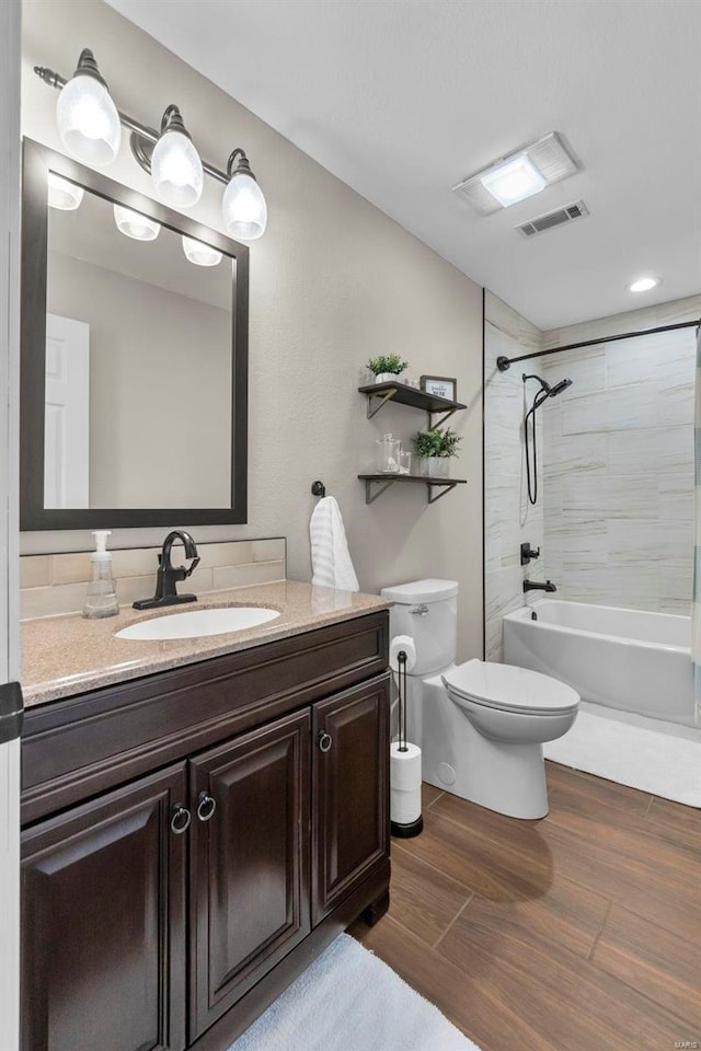 full bathroom featuring toilet, tiled shower / bath, and vanity