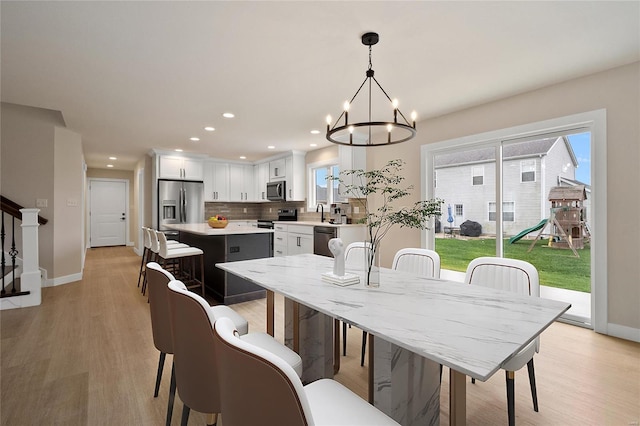 dining area with light hardwood / wood-style floors and a notable chandelier