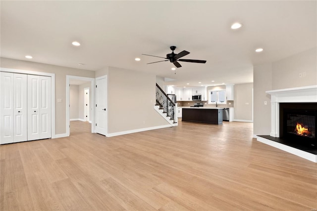 unfurnished living room featuring ceiling fan, light hardwood / wood-style floors, and sink