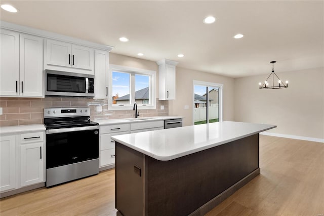 kitchen featuring sink, white cabinets, an inviting chandelier, and appliances with stainless steel finishes