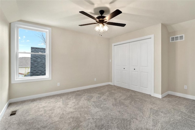 unfurnished bedroom featuring ceiling fan, vaulted ceiling, carpet floors, and a closet