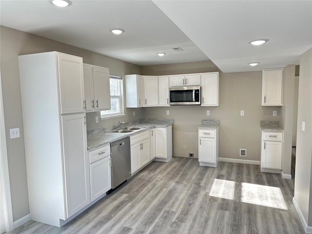 kitchen with white cabinets, appliances with stainless steel finishes, sink, and light wood-type flooring