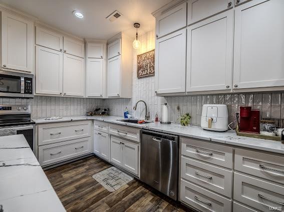 kitchen with white cabinetry, appliances with stainless steel finishes, light stone counters, and dark hardwood / wood-style flooring