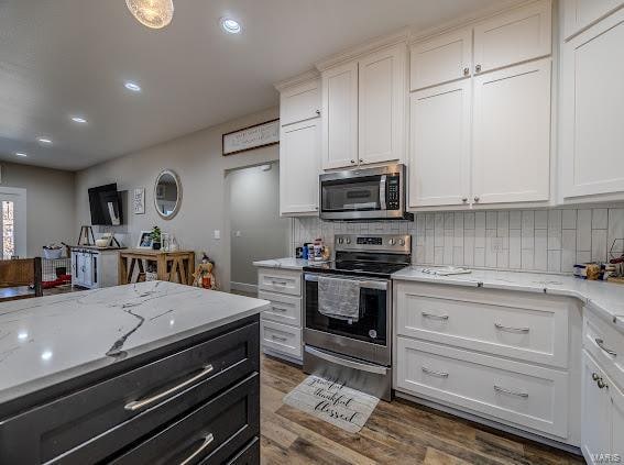 kitchen featuring white cabinetry, appliances with stainless steel finishes, light stone counters, backsplash, and dark wood-type flooring