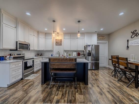 kitchen with dark wood-type flooring, white cabinetry, hanging light fixtures, and stainless steel appliances