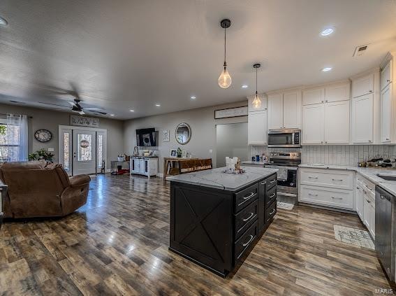 kitchen with a kitchen island, appliances with stainless steel finishes, decorative light fixtures, and white cabinets