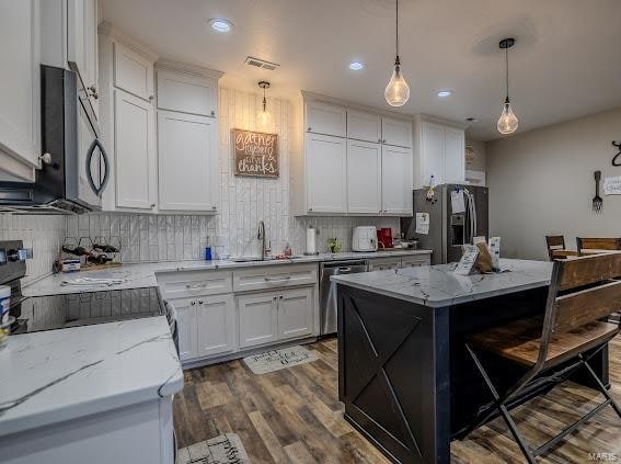 kitchen with white cabinetry, appliances with stainless steel finishes, and decorative light fixtures