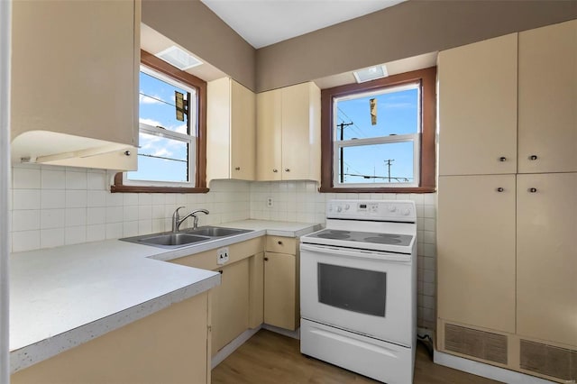 kitchen featuring hardwood / wood-style flooring, electric stove, sink, and cream cabinets