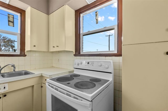 kitchen with cream cabinetry, sink, tasteful backsplash, and electric stove