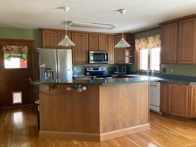 kitchen with appliances with stainless steel finishes, a center island, and light hardwood / wood-style flooring