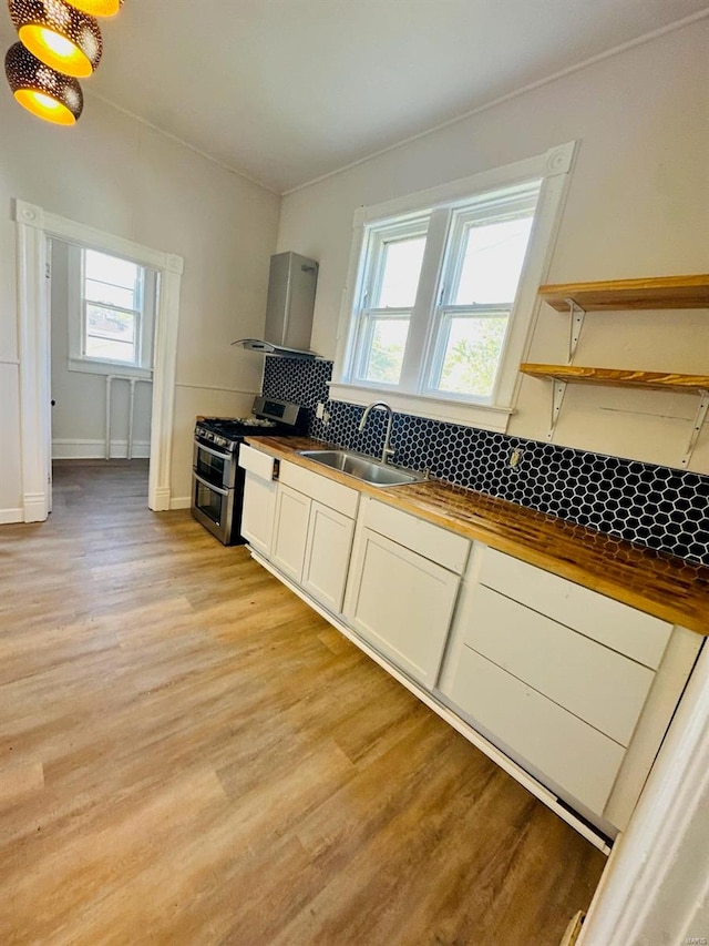 kitchen with light hardwood / wood-style floors, range with two ovens, sink, tasteful backsplash, and wood counters