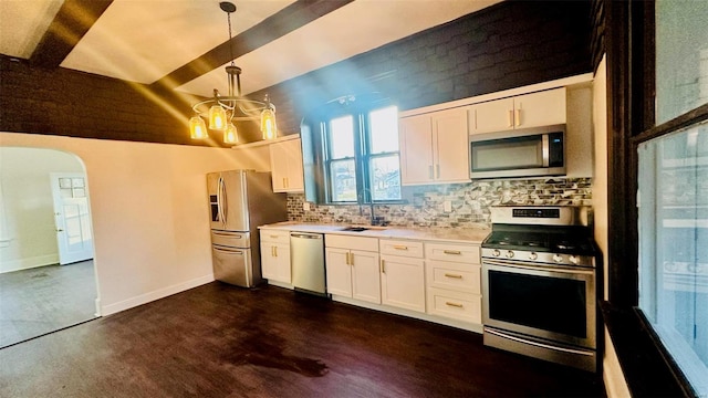 kitchen with white cabinets, appliances with stainless steel finishes, hanging light fixtures, and beamed ceiling