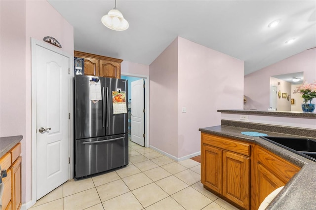 kitchen featuring light tile patterned flooring, stainless steel refrigerator, sink, decorative light fixtures, and lofted ceiling