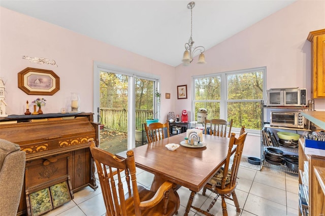 tiled dining space featuring a chandelier, lofted ceiling, and a healthy amount of sunlight