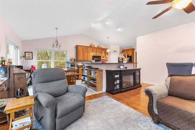 living room featuring ceiling fan, light wood-type flooring, and vaulted ceiling