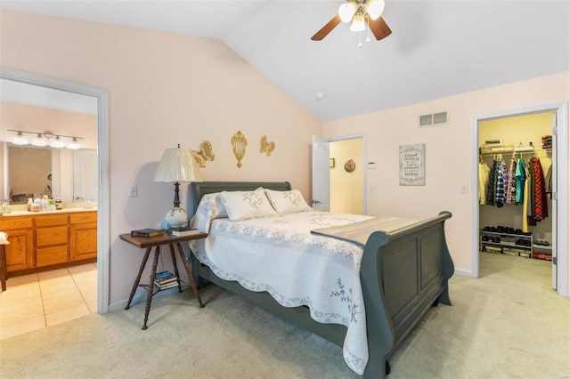 bedroom featuring vaulted ceiling, light carpet, ceiling fan, and ensuite bathroom