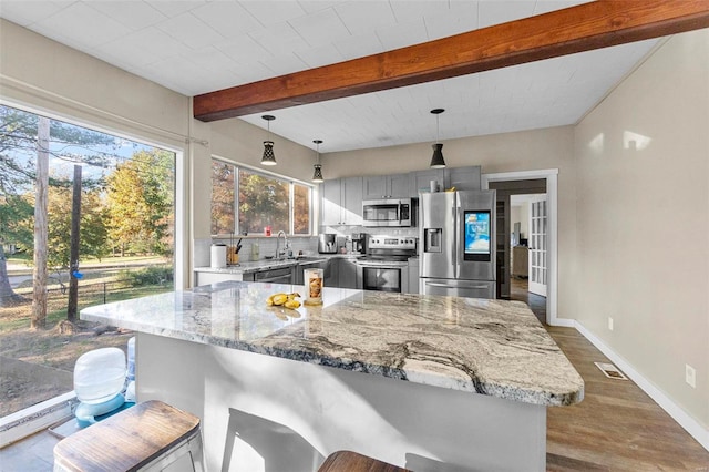 kitchen featuring stainless steel appliances, dark hardwood / wood-style flooring, a breakfast bar area, beamed ceiling, and pendant lighting