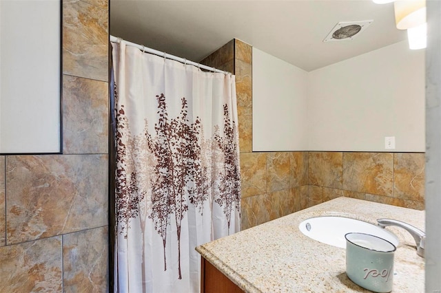 bathroom featuring vanity and tile walls