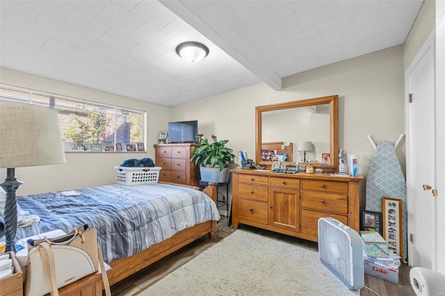 bedroom with beamed ceiling and hardwood / wood-style floors