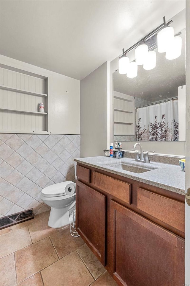 bathroom featuring toilet, vanity, tile walls, and tile patterned floors