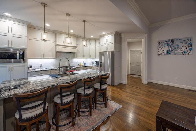 kitchen featuring stainless steel appliances, hanging light fixtures, dark wood-type flooring, and stone counters