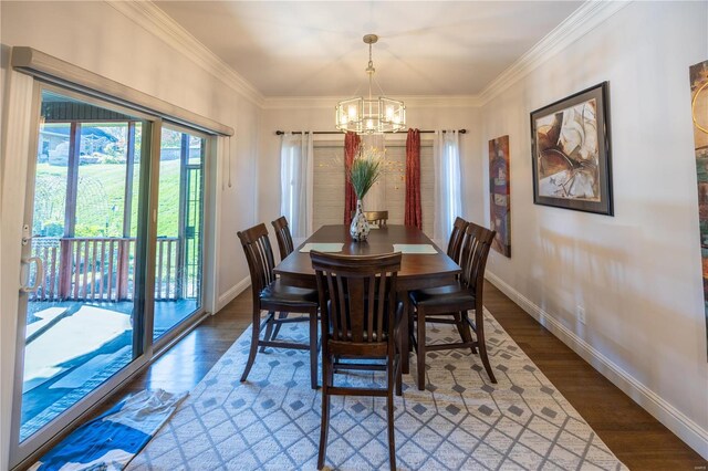 dining space with dark wood-type flooring, an inviting chandelier, a barn door, and crown molding