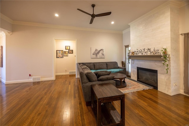 living room featuring dark wood-type flooring, ceiling fan, ornamental molding, and a fireplace