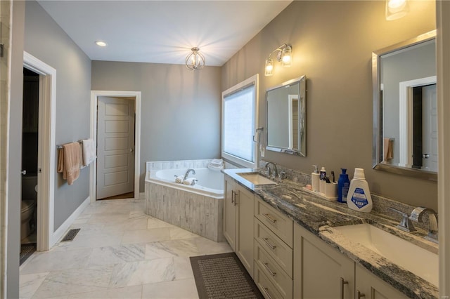 bathroom with tiled bath, vanity, and toilet