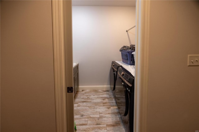 clothes washing area with independent washer and dryer and light hardwood / wood-style flooring