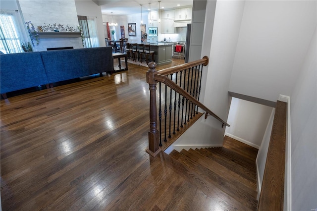 stairs with wood-type flooring and a notable chandelier